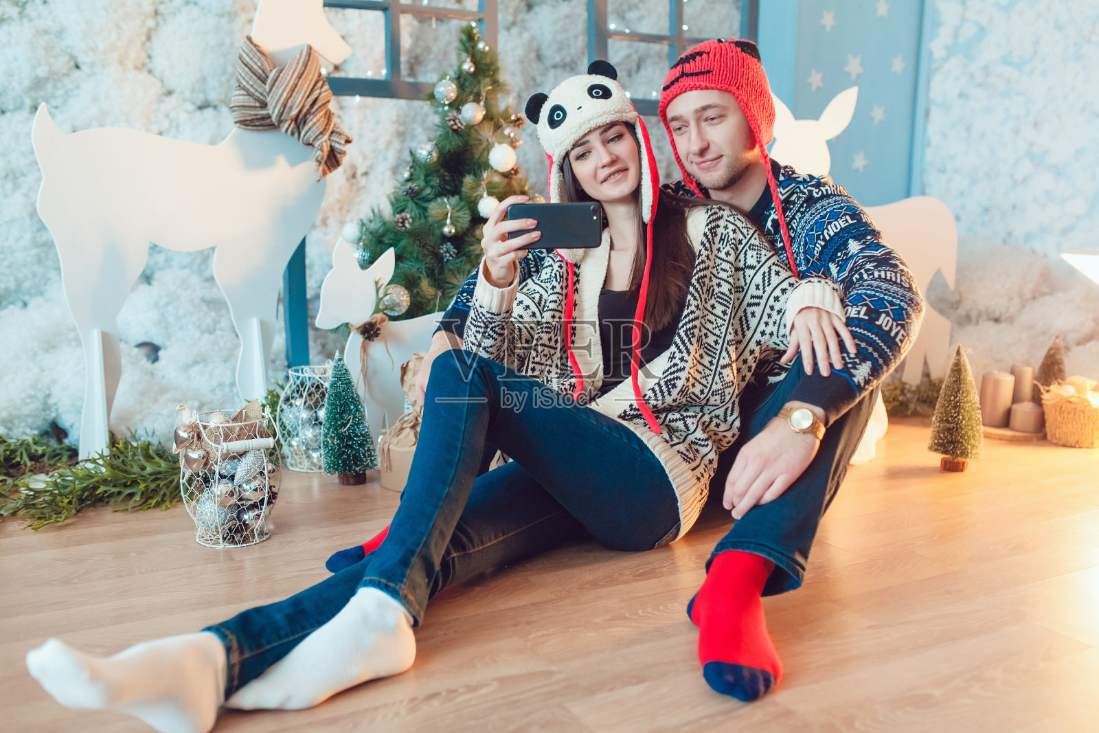 一对戴着滑稽帽子的漂亮年轻夫妇坐在背景上照片摄影图片