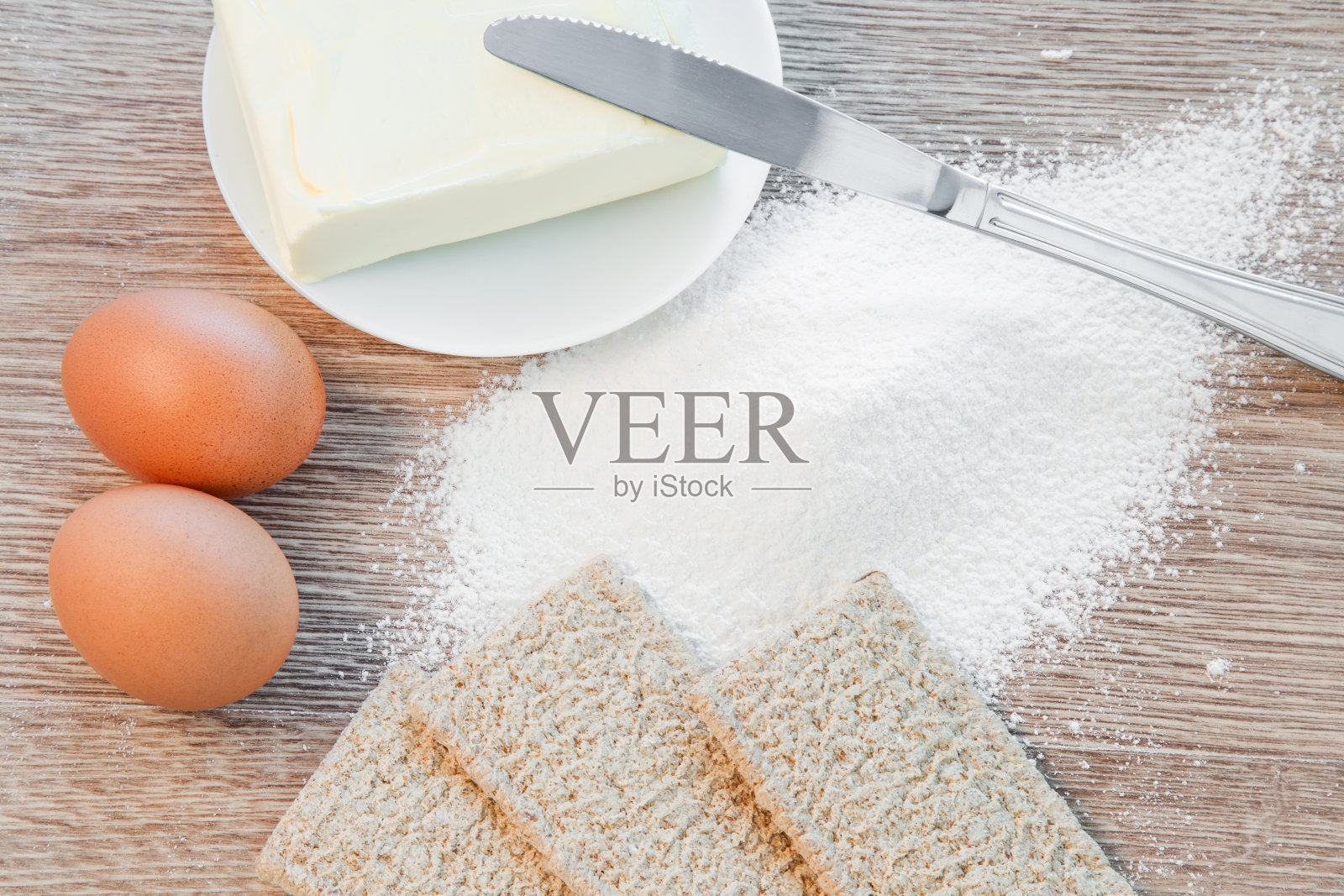 面粉，鸡蛋，黄油和酥脆的面包放在木桌上。照片摄影图片