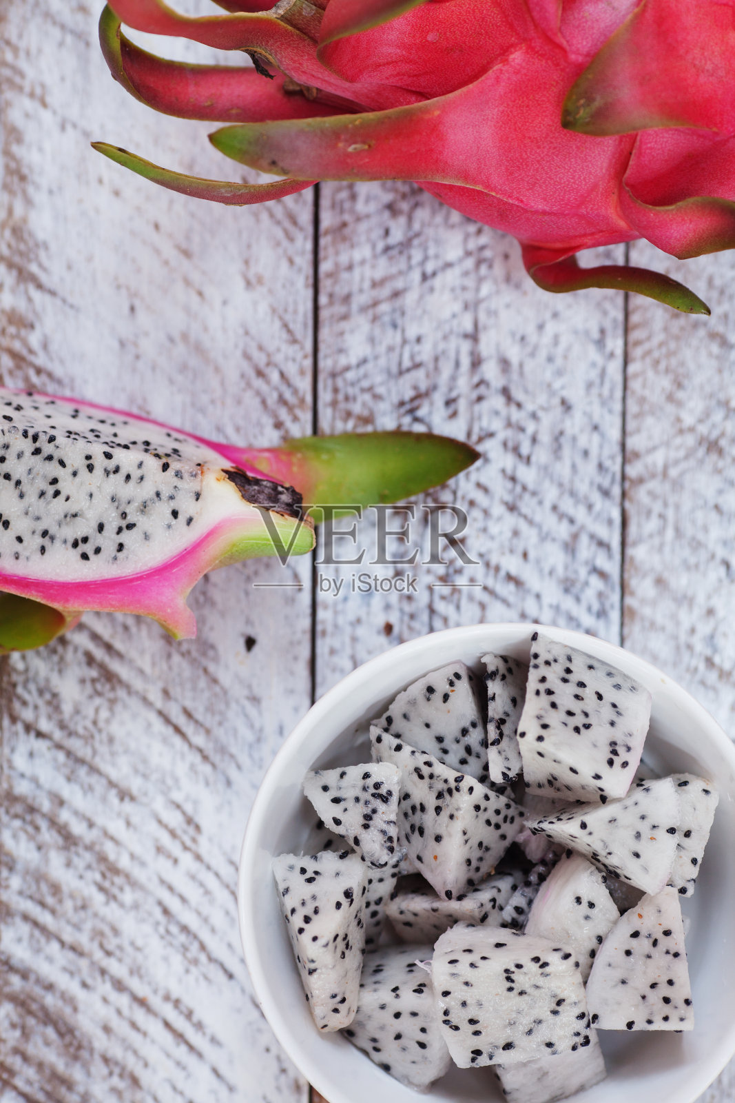 火龙果碎片放在木桌上的盘子里照片摄影图片