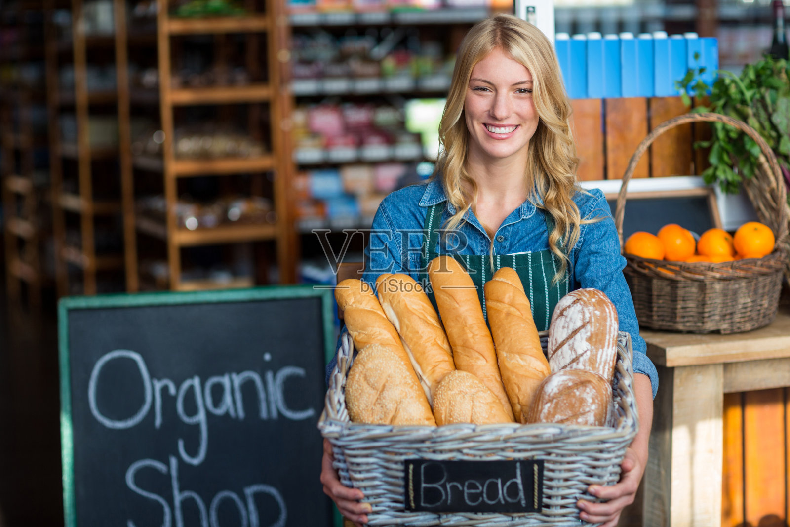 微笑的女人拿着一篮长棍面包在有机商店照片摄影图片