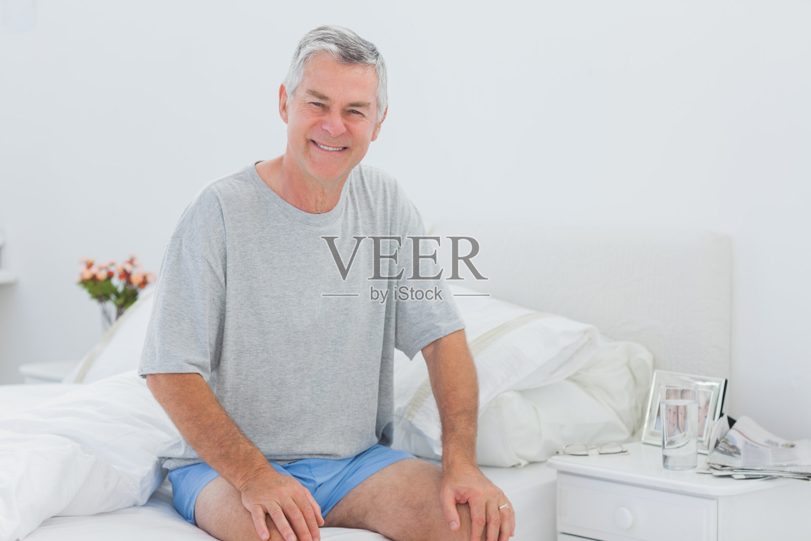 男人微笑着坐在床上照片摄影图片