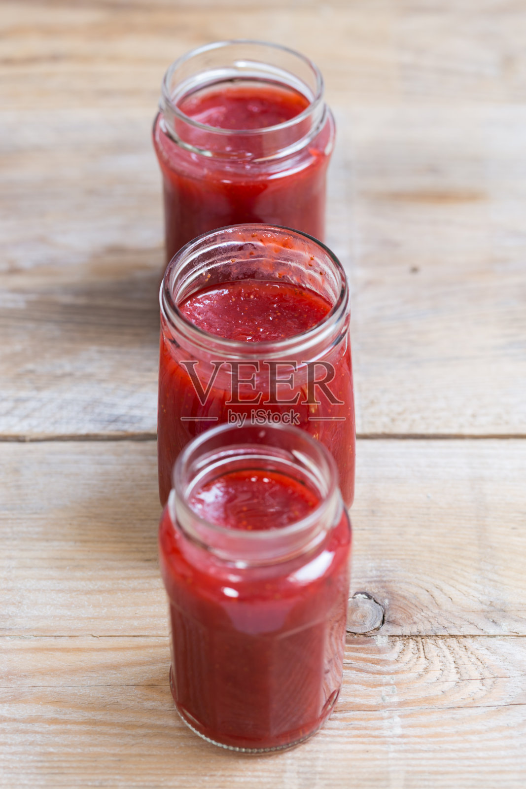 放在木头上的罐子里的草莓酱照片摄影图片