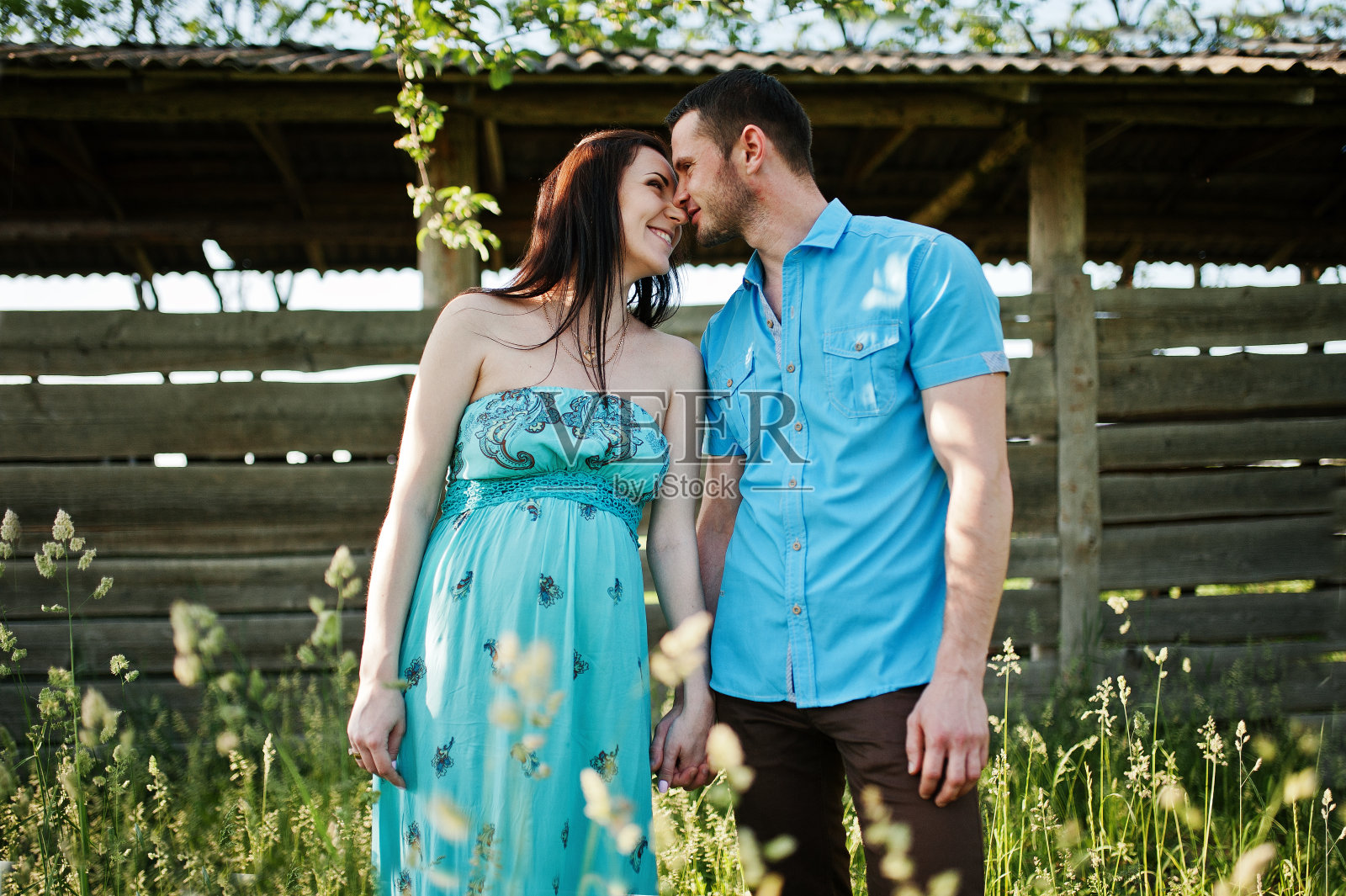 一对幸福的怀孕夫妇穿着绿松石裙在花园里照片摄影图片