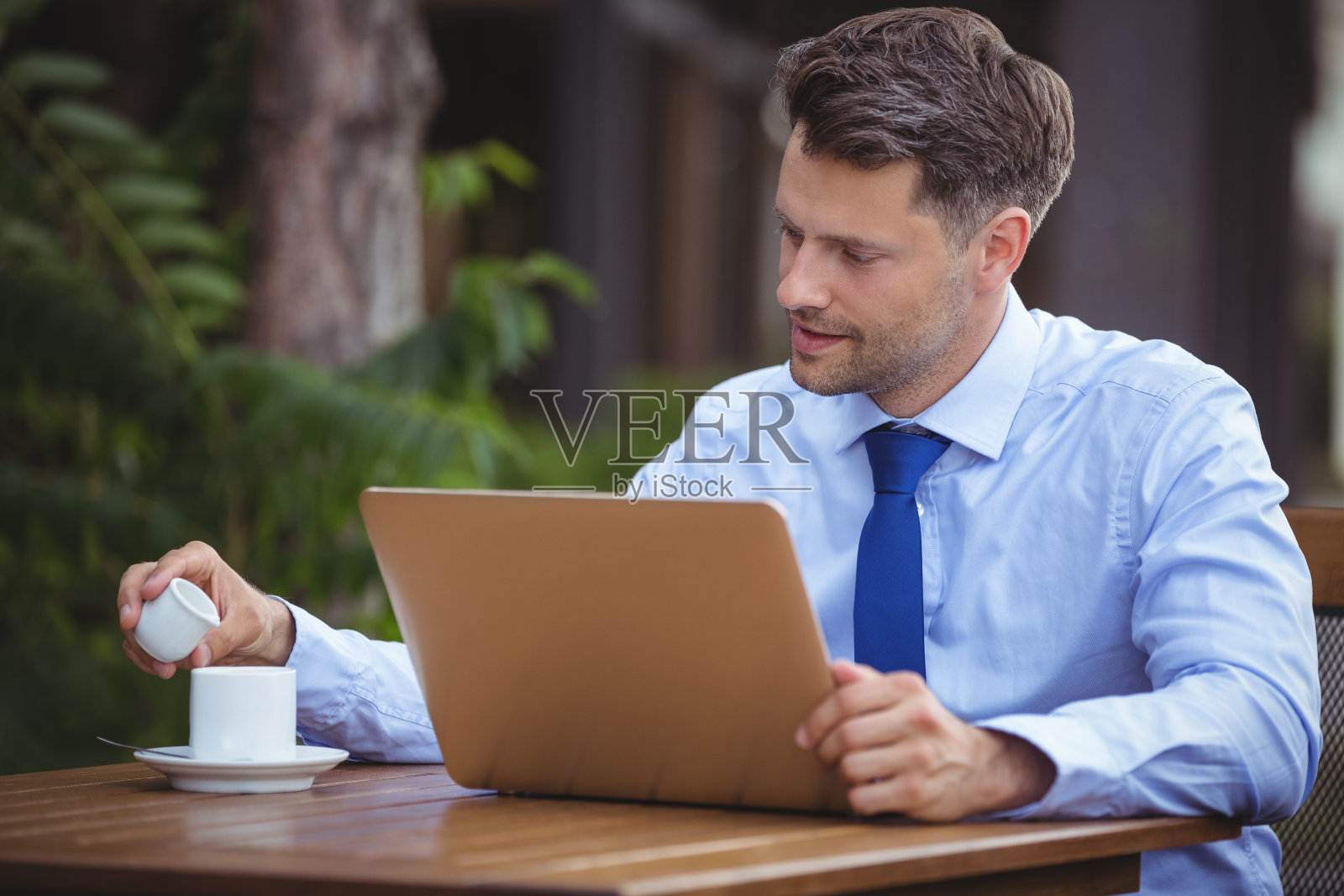英俊的商人一边喝茶一边用笔记本电脑照片摄影图片