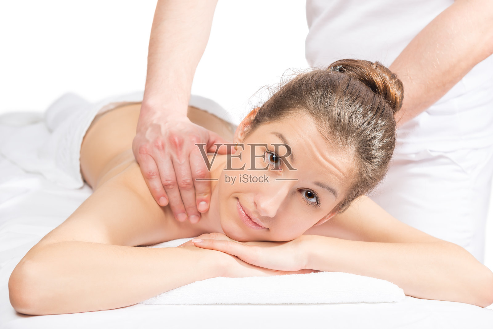 美丽的黑发美人在按摩床上，按摩师的手放在她的背上照片摄影图片