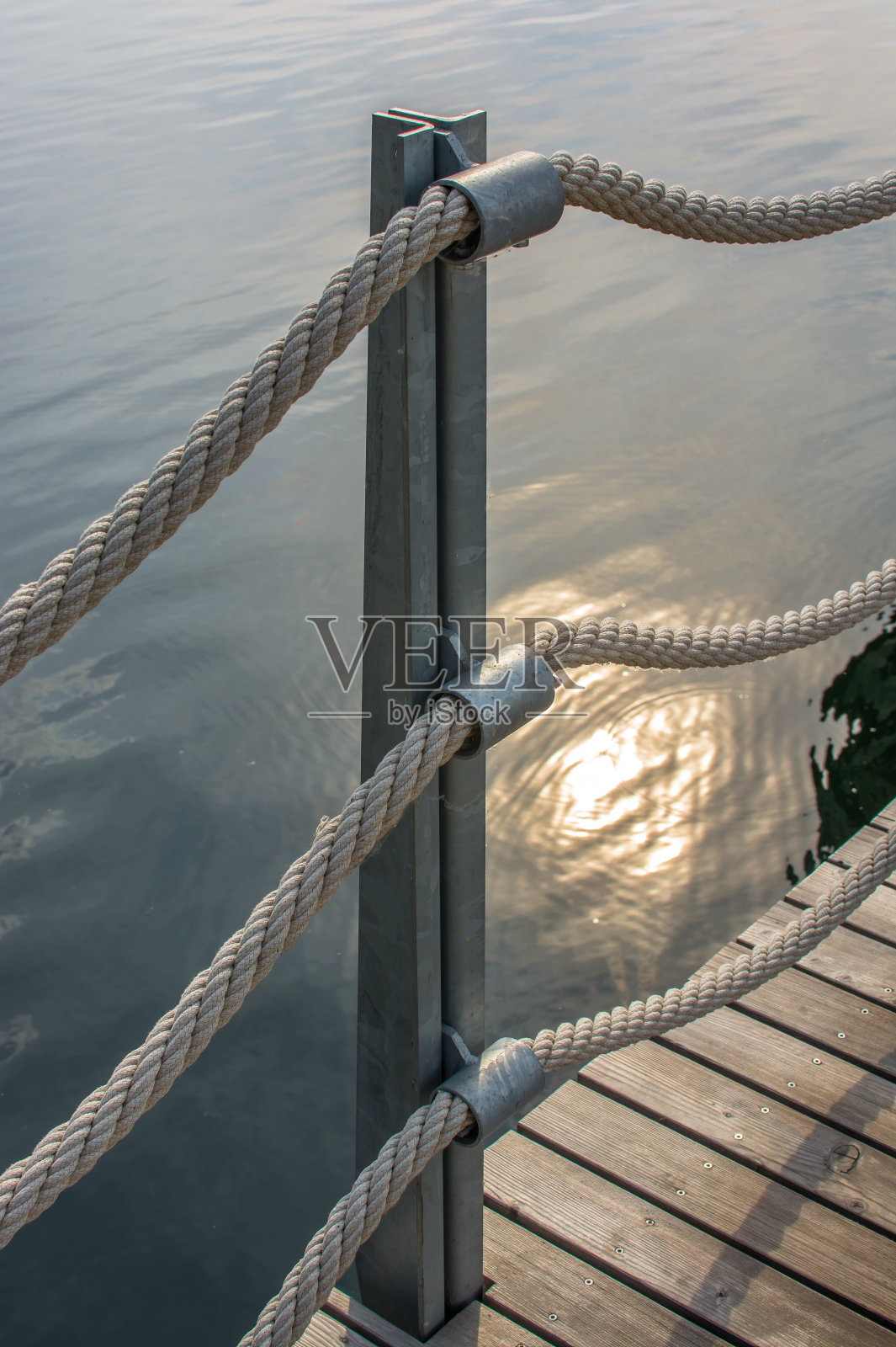 在平静的水面上有粗绳的栏杆照片摄影图片