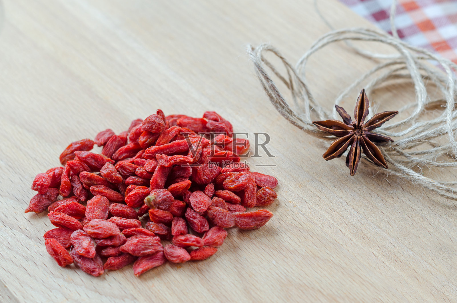 枸杞和丁香放在木板上。照片摄影图片