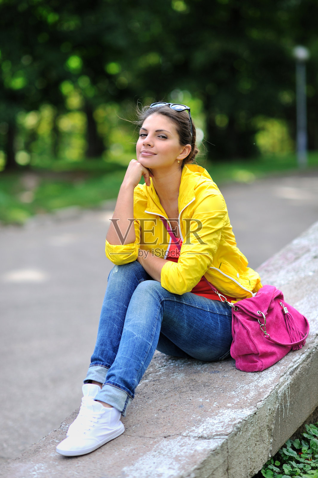 美丽的女孩手托着下巴坐在公园里