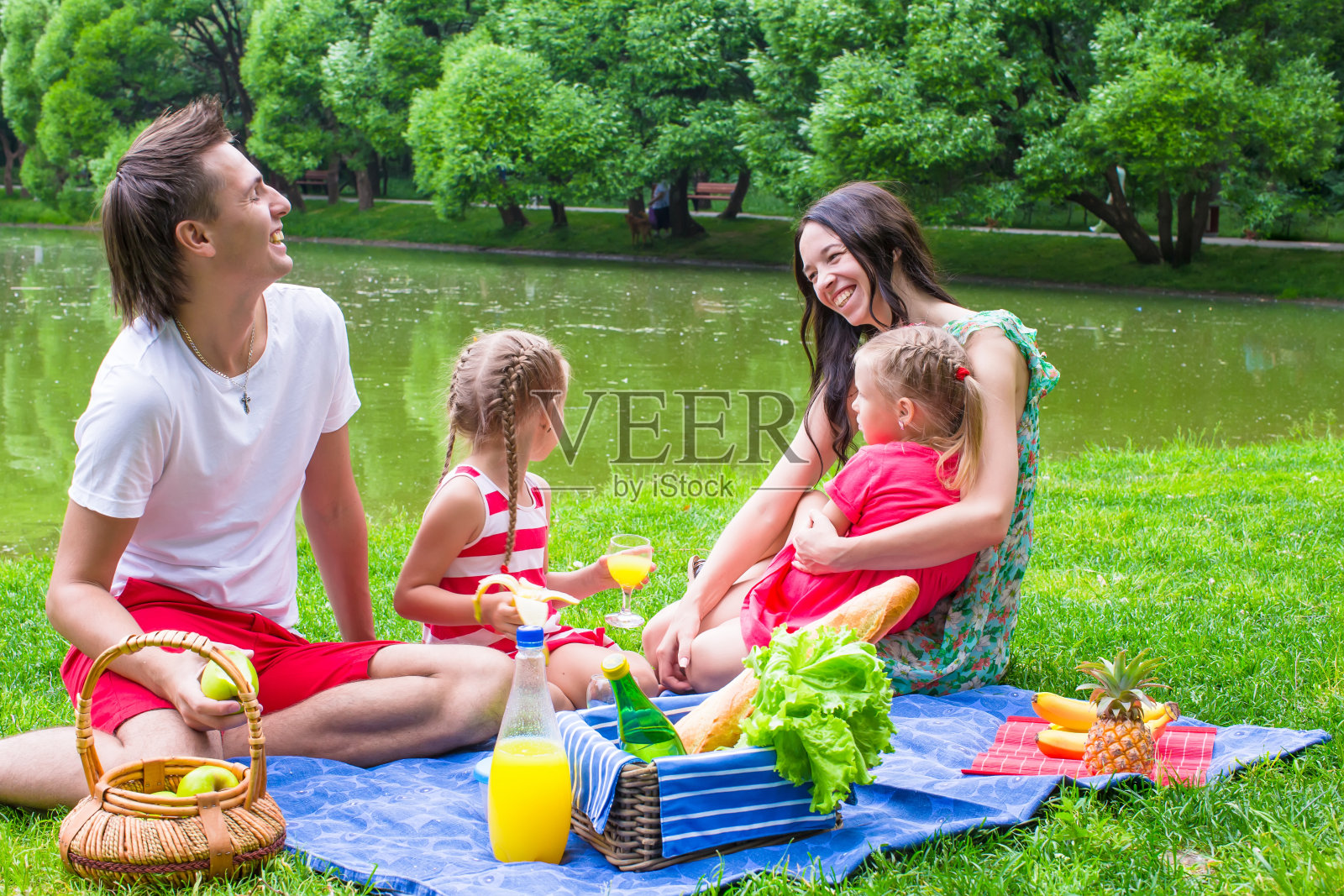 快乐的年轻家庭在湖边野餐照片摄影图片