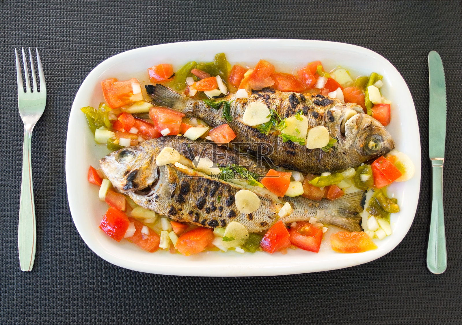 烤鲷鱼配地中海番茄沙拉。典型的地中海菜肴。照片摄影图片