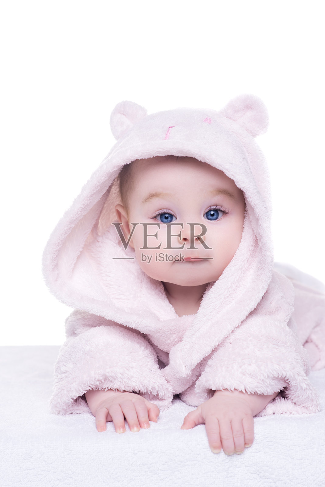 穿着粉色浴衣的女婴躺在她的肚子上照片摄影图片