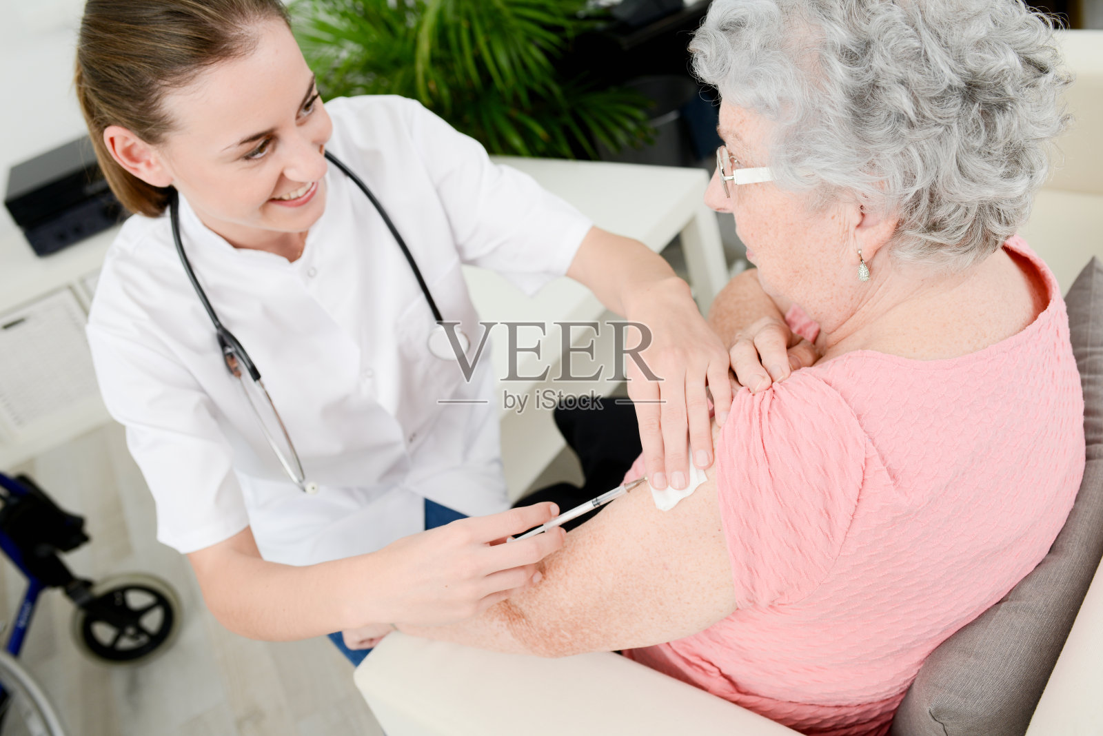 开朗的年轻护士给家中的老年妇女注射疫苗照片摄影图片