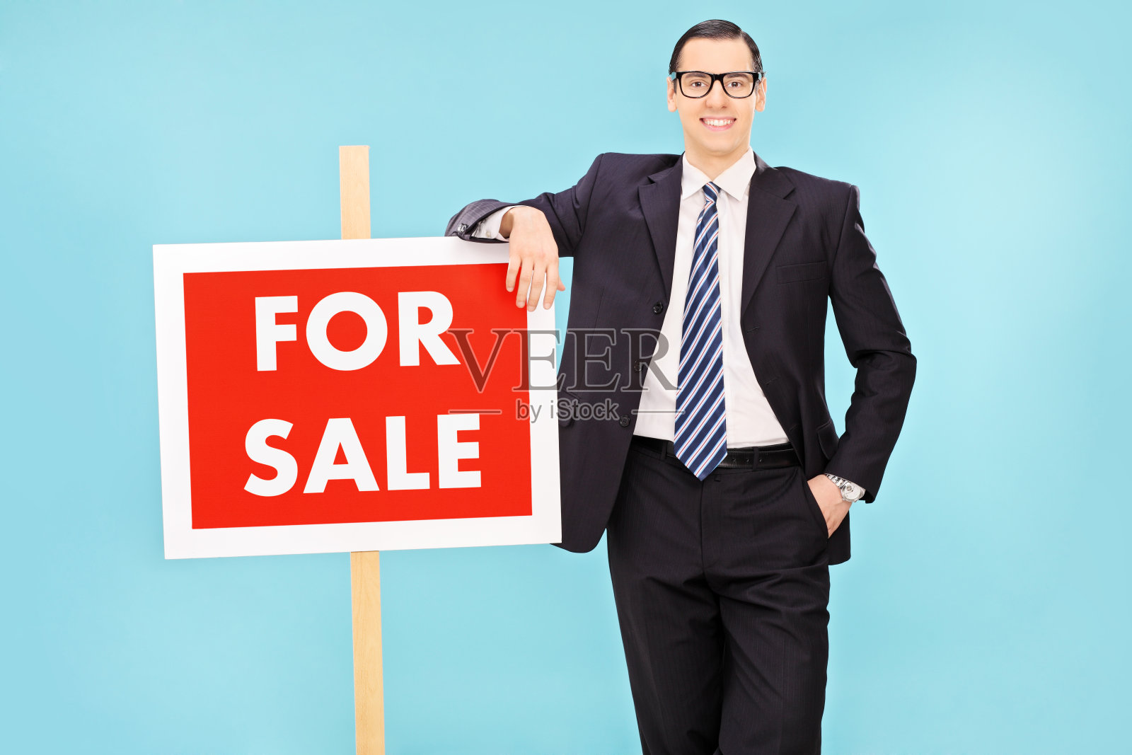 商人站在出售标志旁边照片摄影图片
