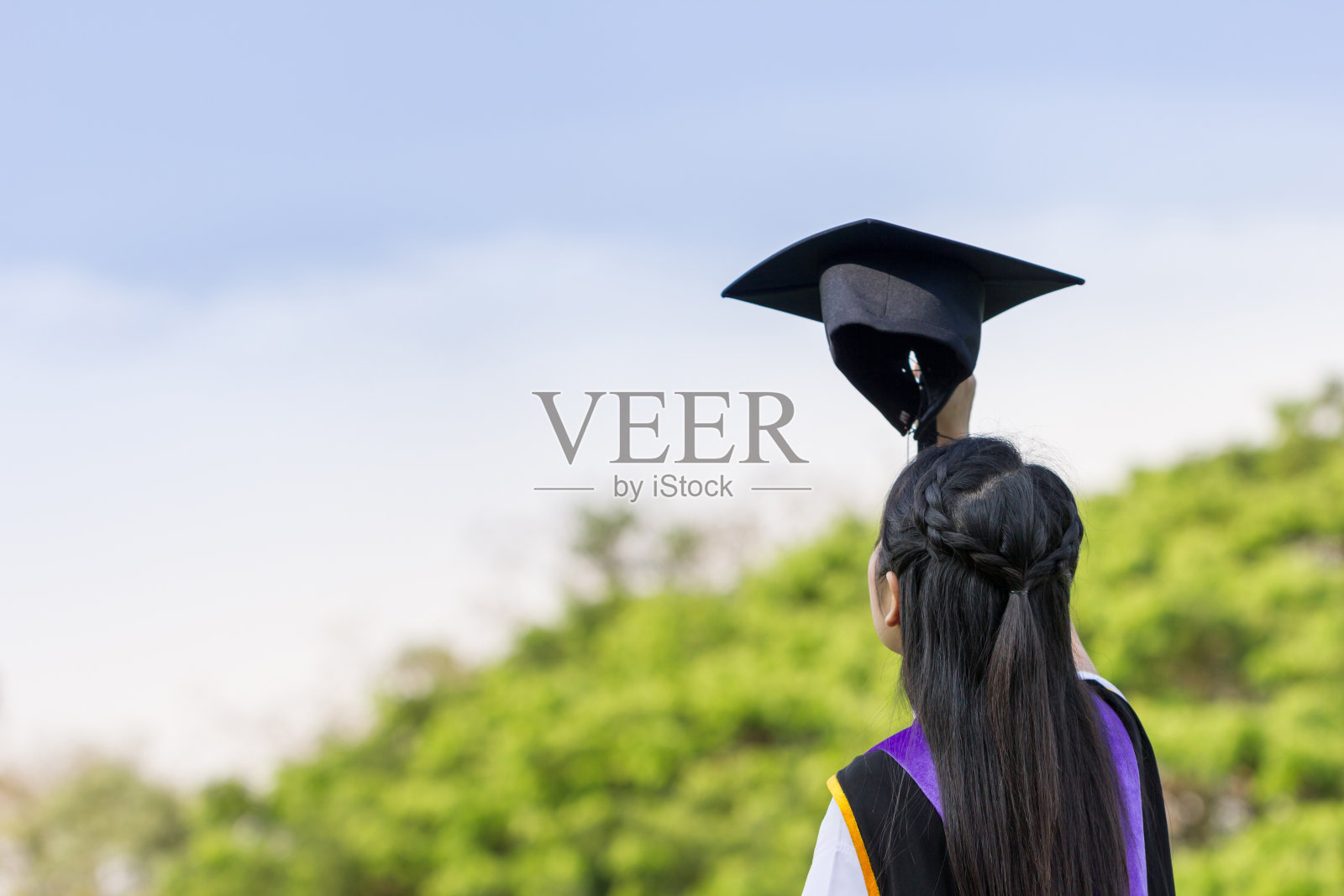 研究生女孩的后视图与手拿帽子。照片摄影图片