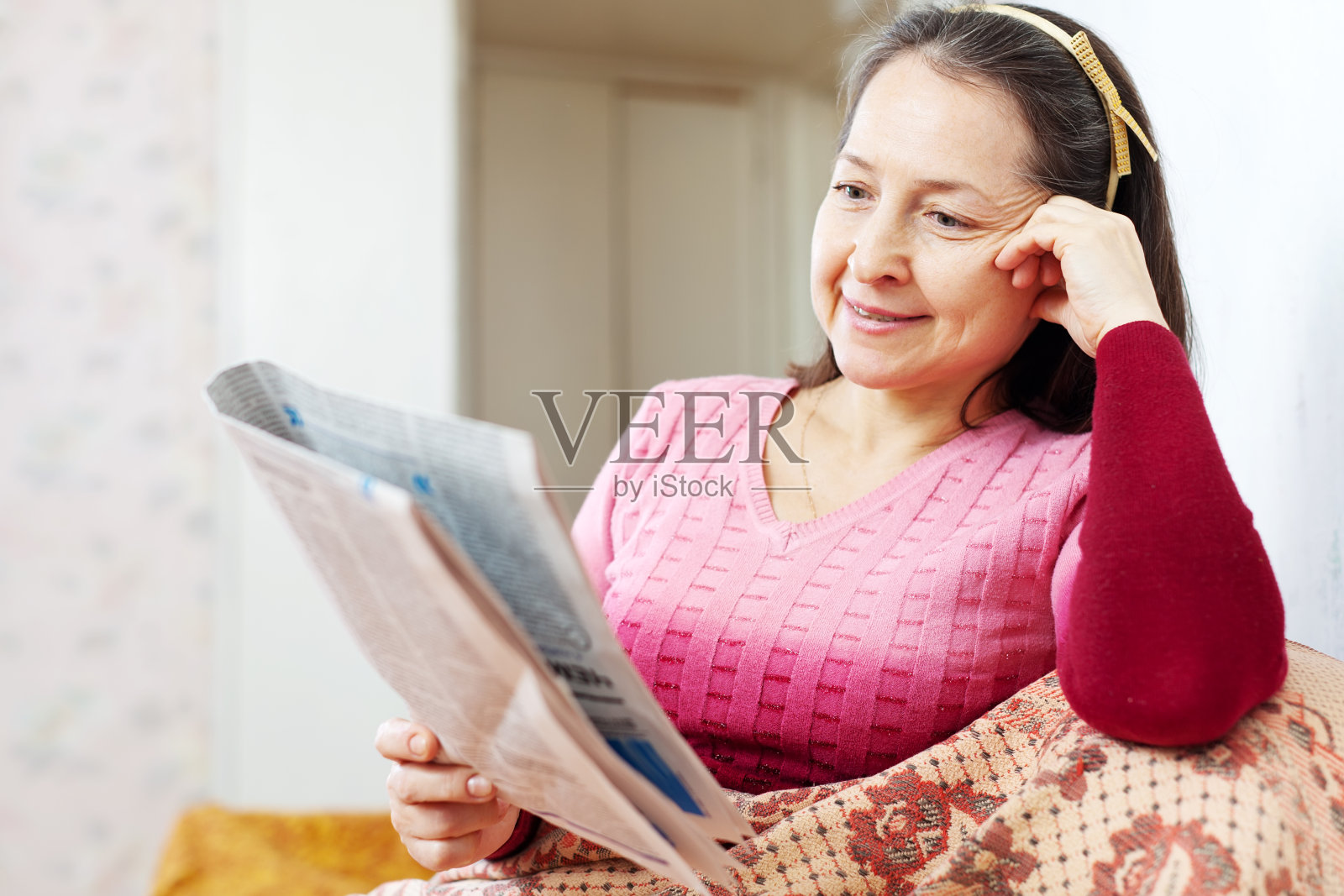 成熟的女人坐在沙发上看报纸照片摄影图片
