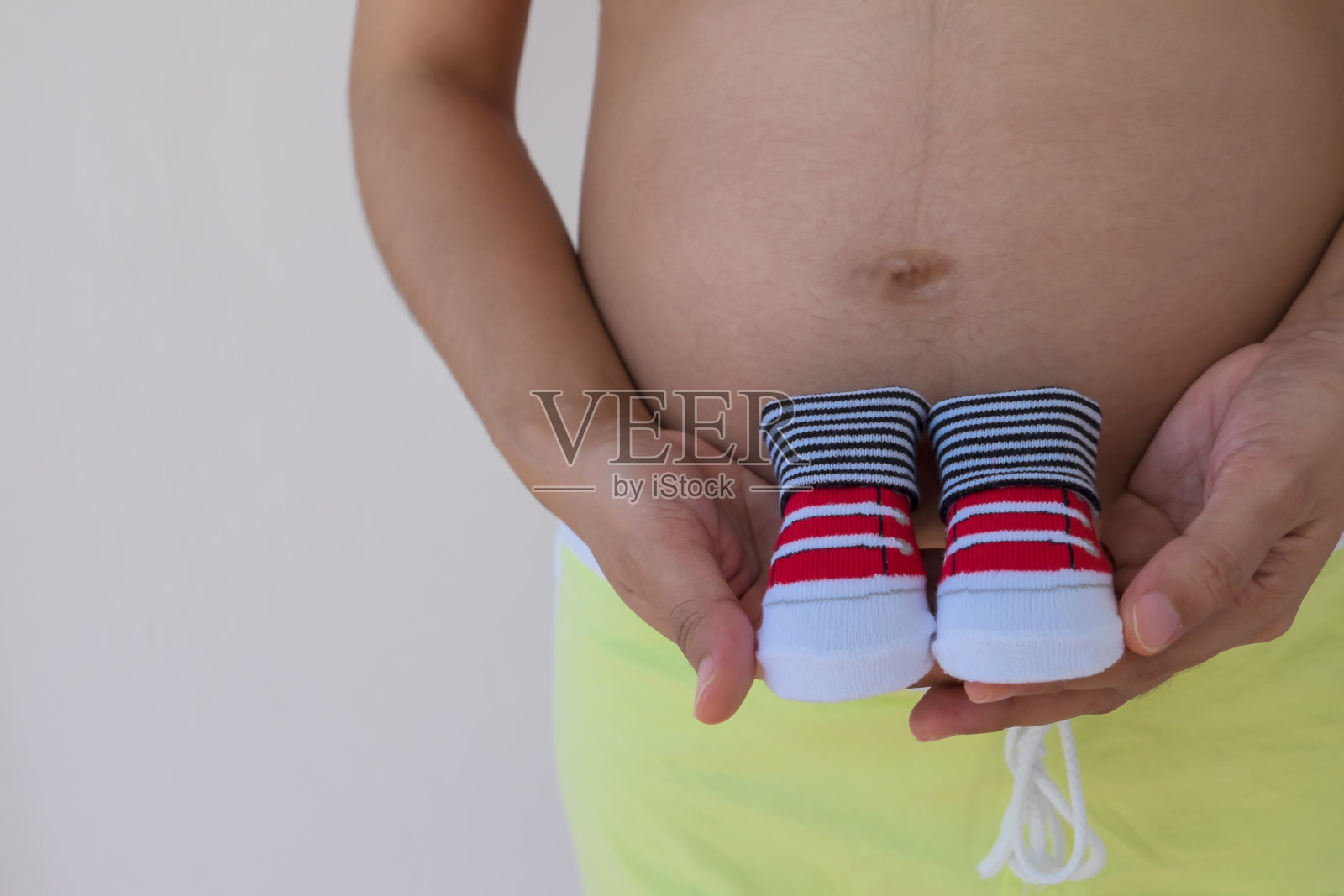 一个孕妇拿着婴儿鞋的特写镜头。照片摄影图片