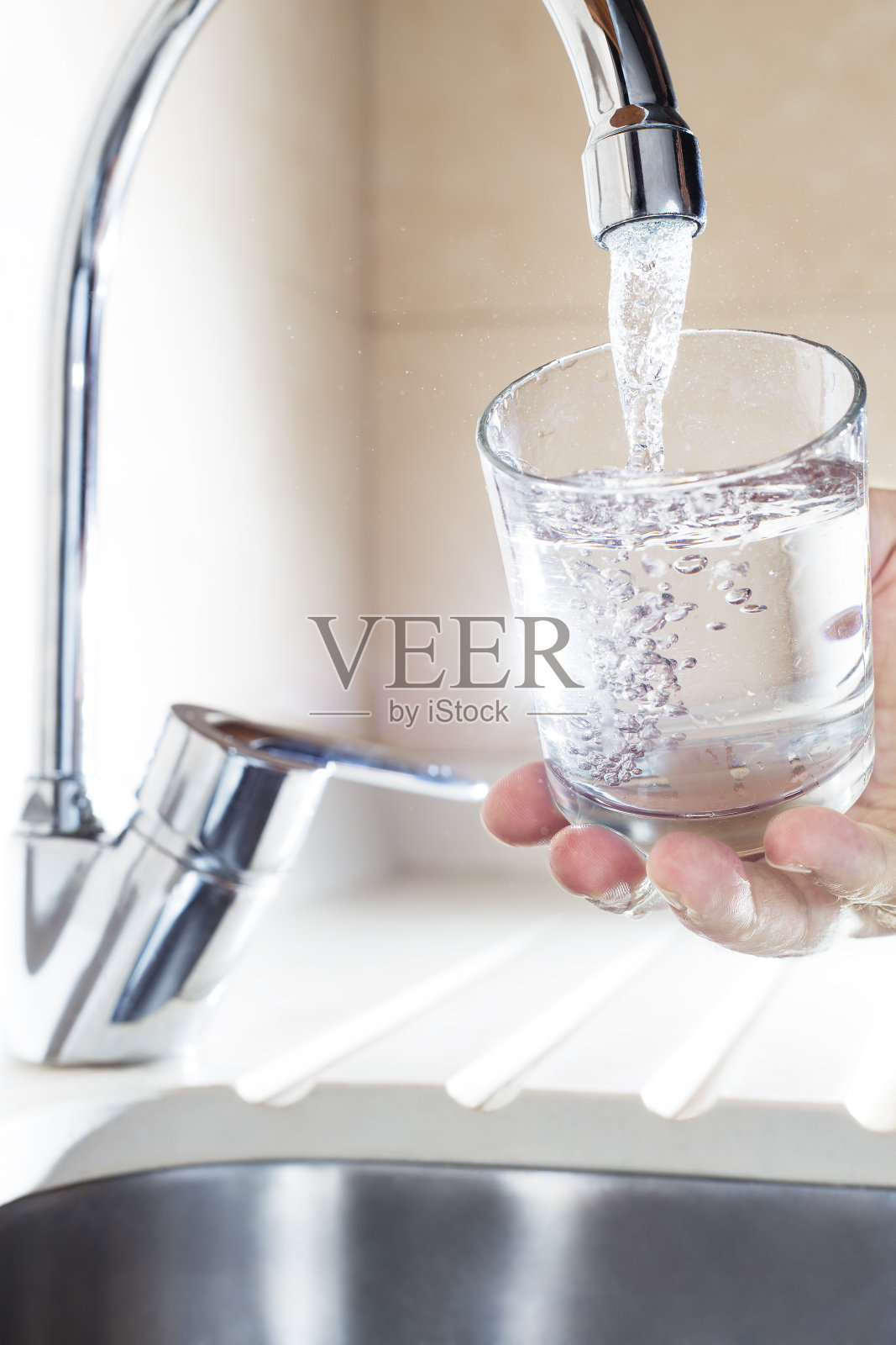 从厨房的水龙头里倒满一杯水照片摄影图片