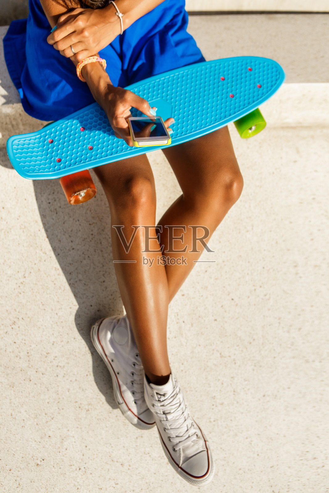 穿着蓝色裙子的漂亮黑人女孩在玩手机照片摄影图片