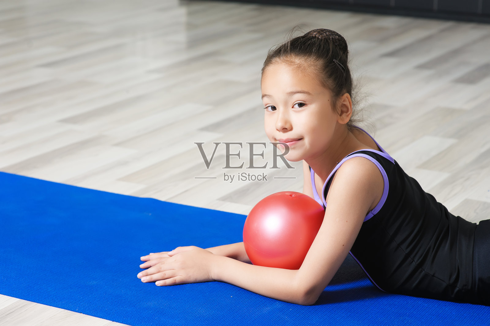 年轻女子体操运动员的肖像与红色的球。照片摄影图片