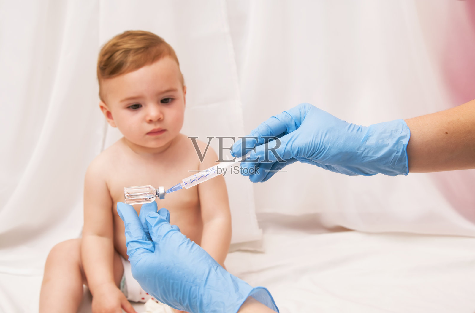 医生拿着注射器给生病的婴儿注射疫苗照片摄影图片
