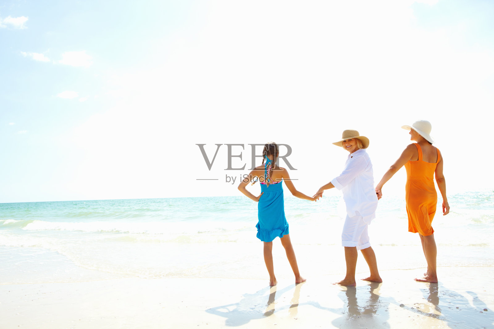 老妇人带着女儿和孙女在海滩上散步照片摄影图片