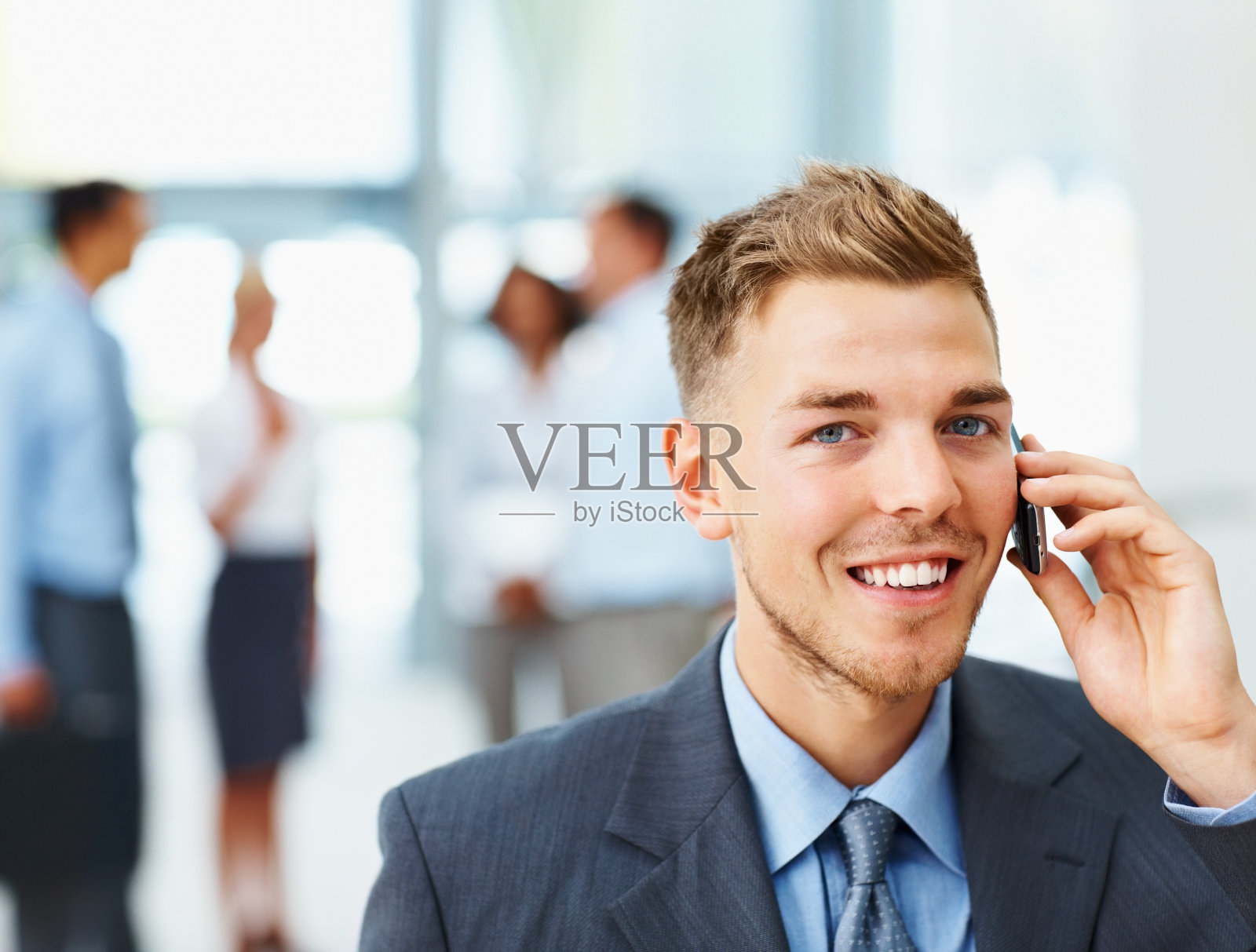 快乐的商人用手机和同事在后台照片摄影图片