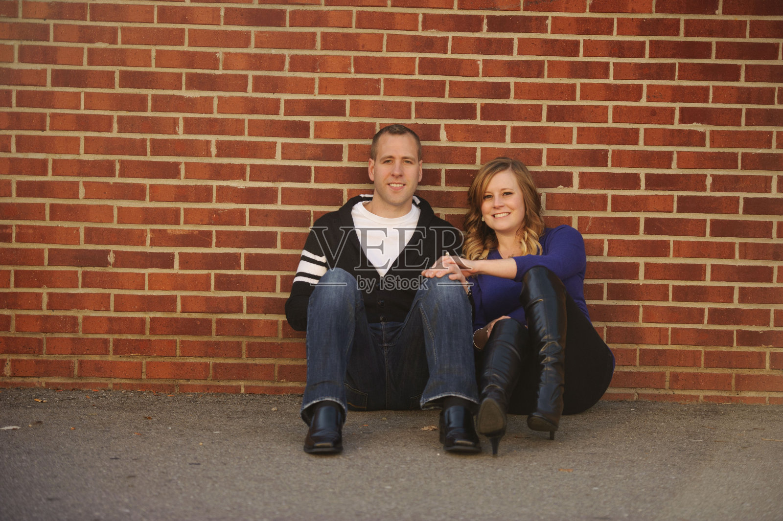 坐在砖墙旁的夫妇照片摄影图片