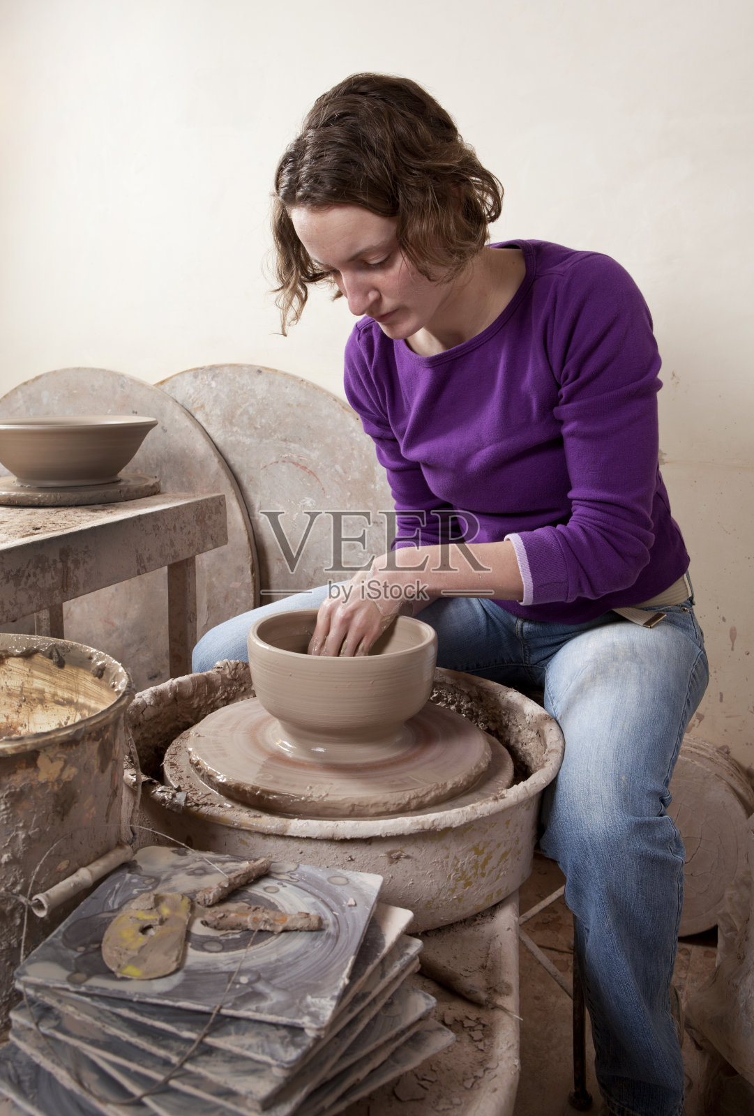 在陶器轮上工作的女人。照片摄影图片