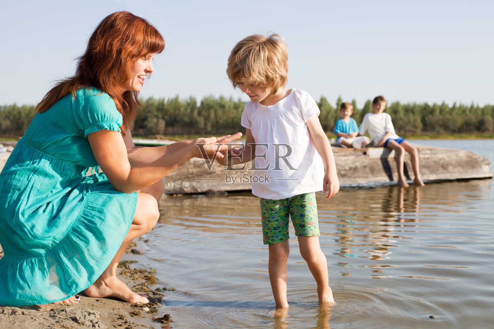 母亲在河边给女儿看东西。照片摄影图片