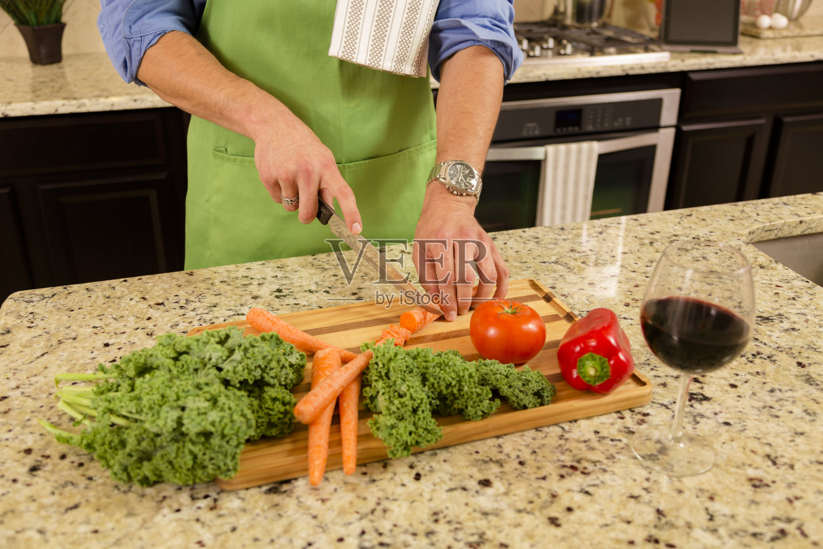 现代人在家里的厨房里做饭。沙拉,蔬菜,葡萄酒。照片摄影图片