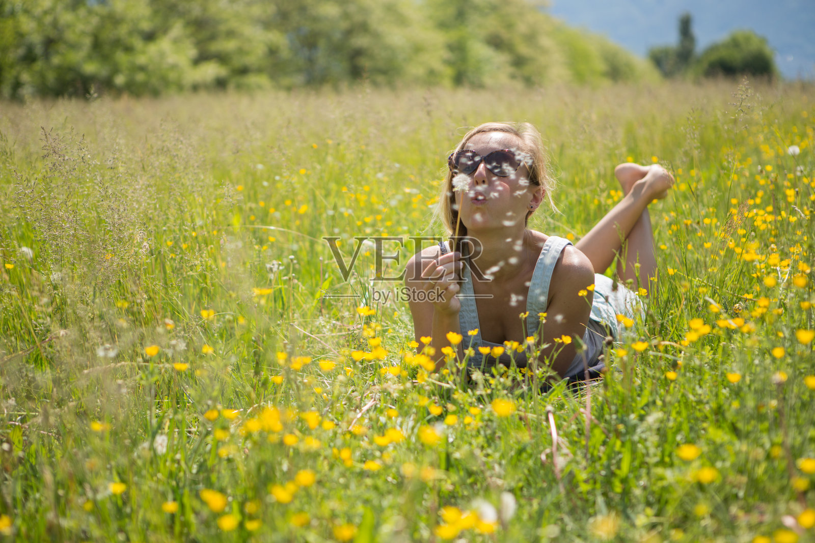 在田野里吹花的年轻女人照片摄影图片