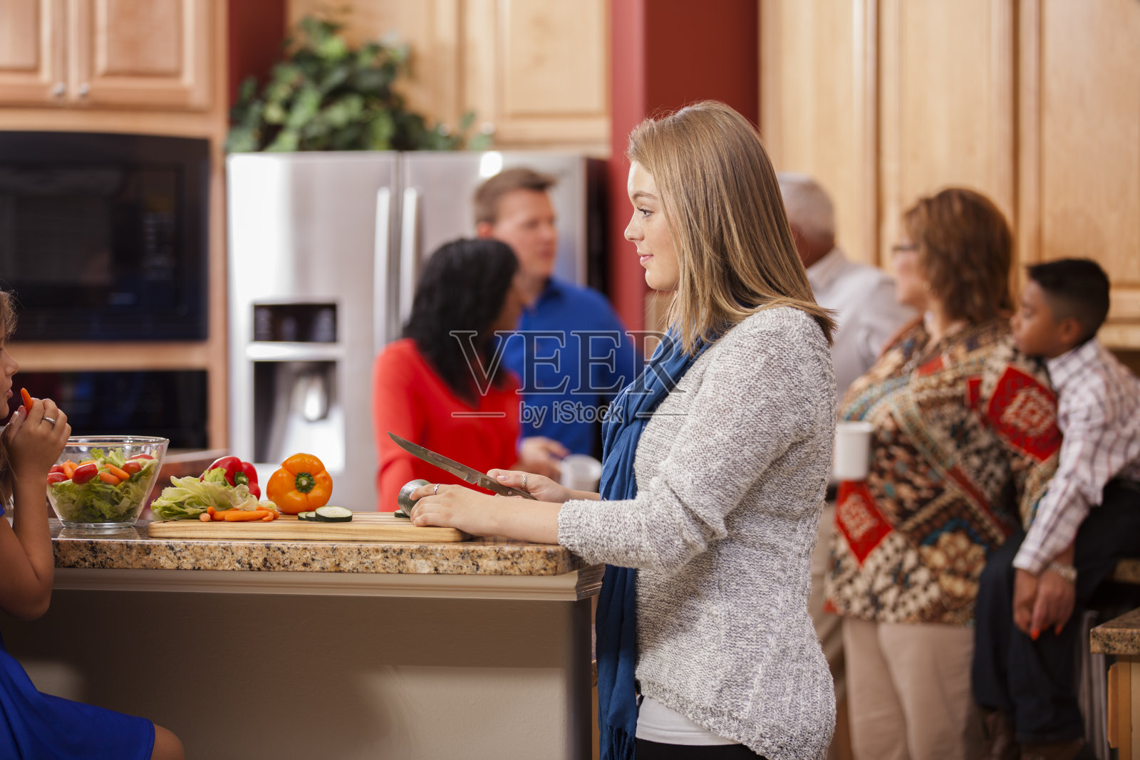 家人、朋友聚在厨房准备饭菜。母亲的前景。照片摄影图片