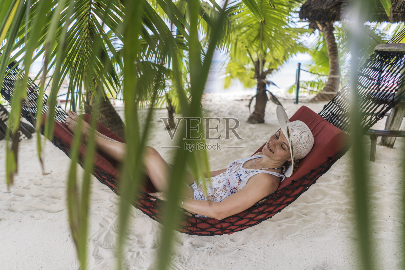 年轻女子放松地享受在吊床上的海滩。照片摄影图片