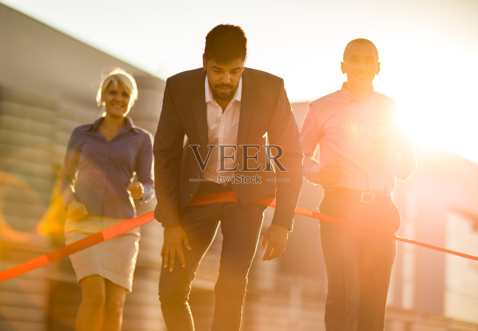 疲惫的非裔美国商人在日落时越过终点线。照片摄影图片