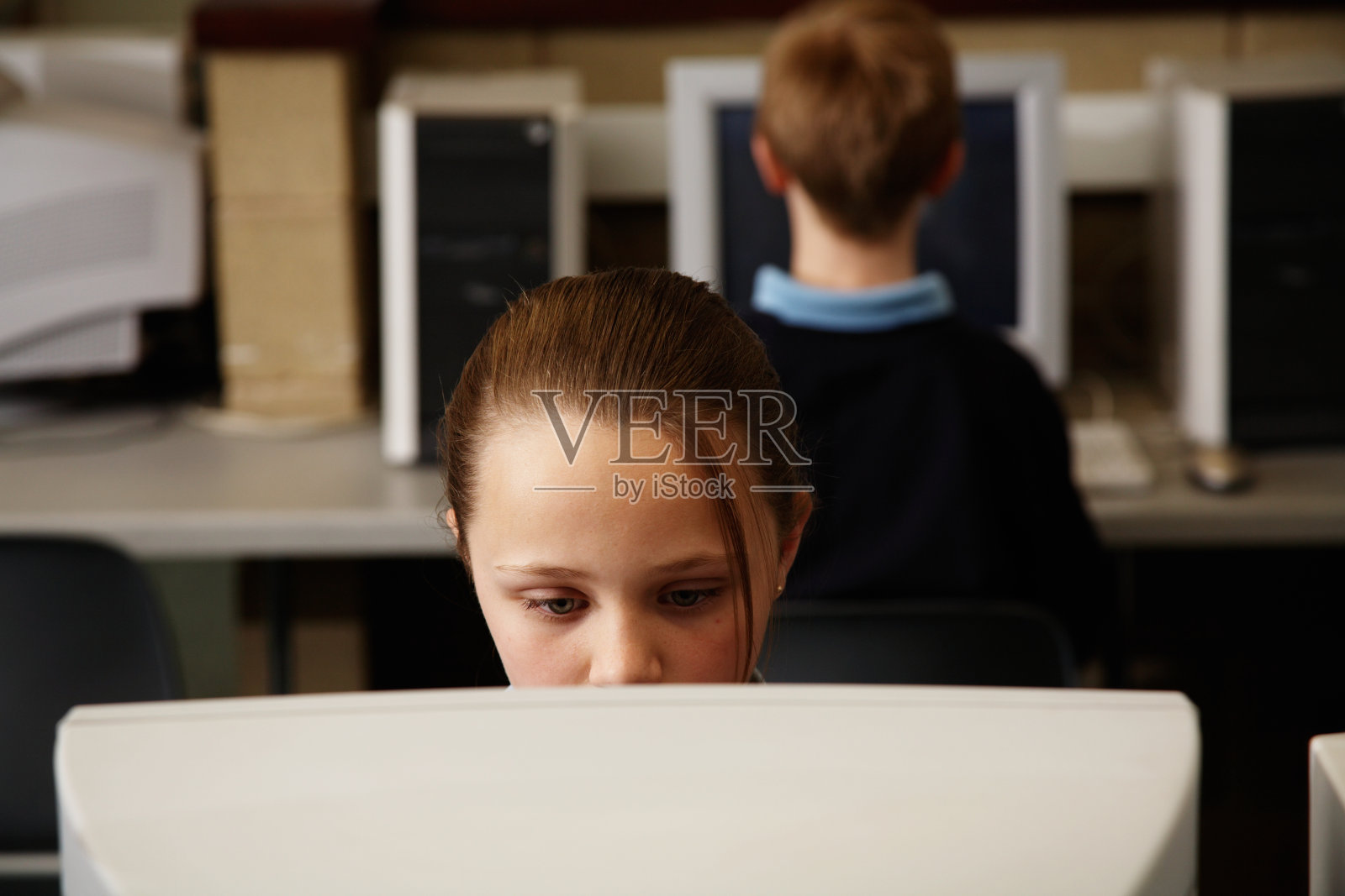 女生(11-13)在课堂上使用电脑，男生(11-13)在后面照片摄影图片