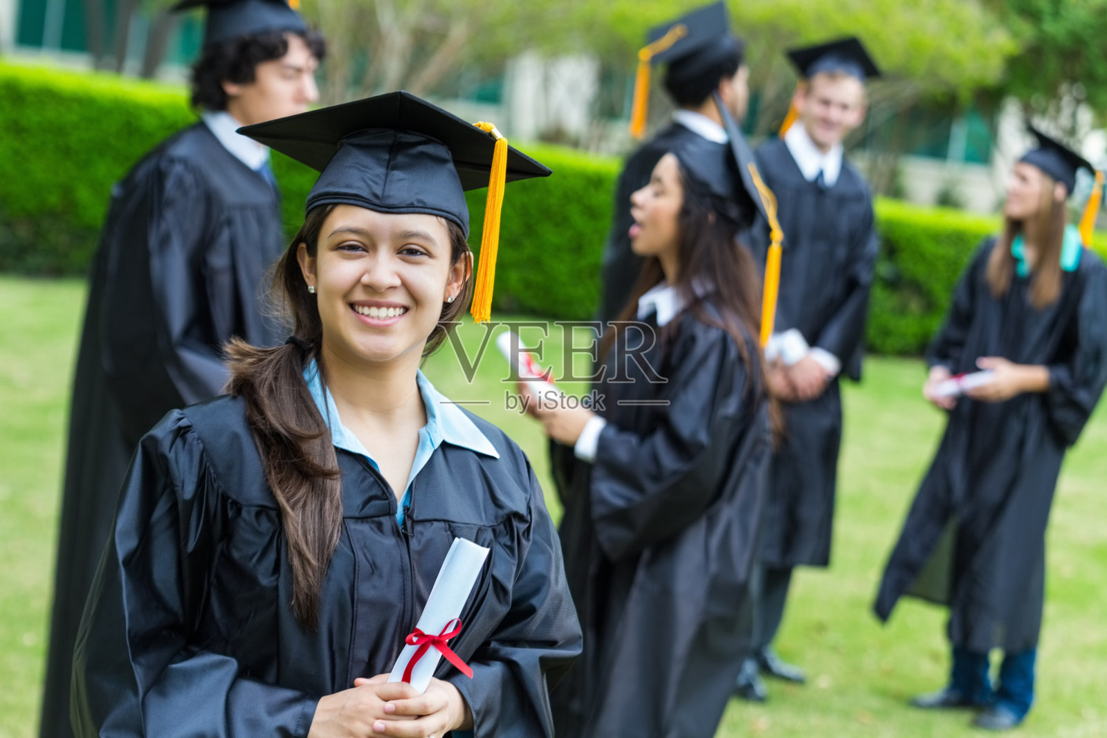 毕业典礼后，快乐的学生聚集在学校的草坪上照片摄影图片