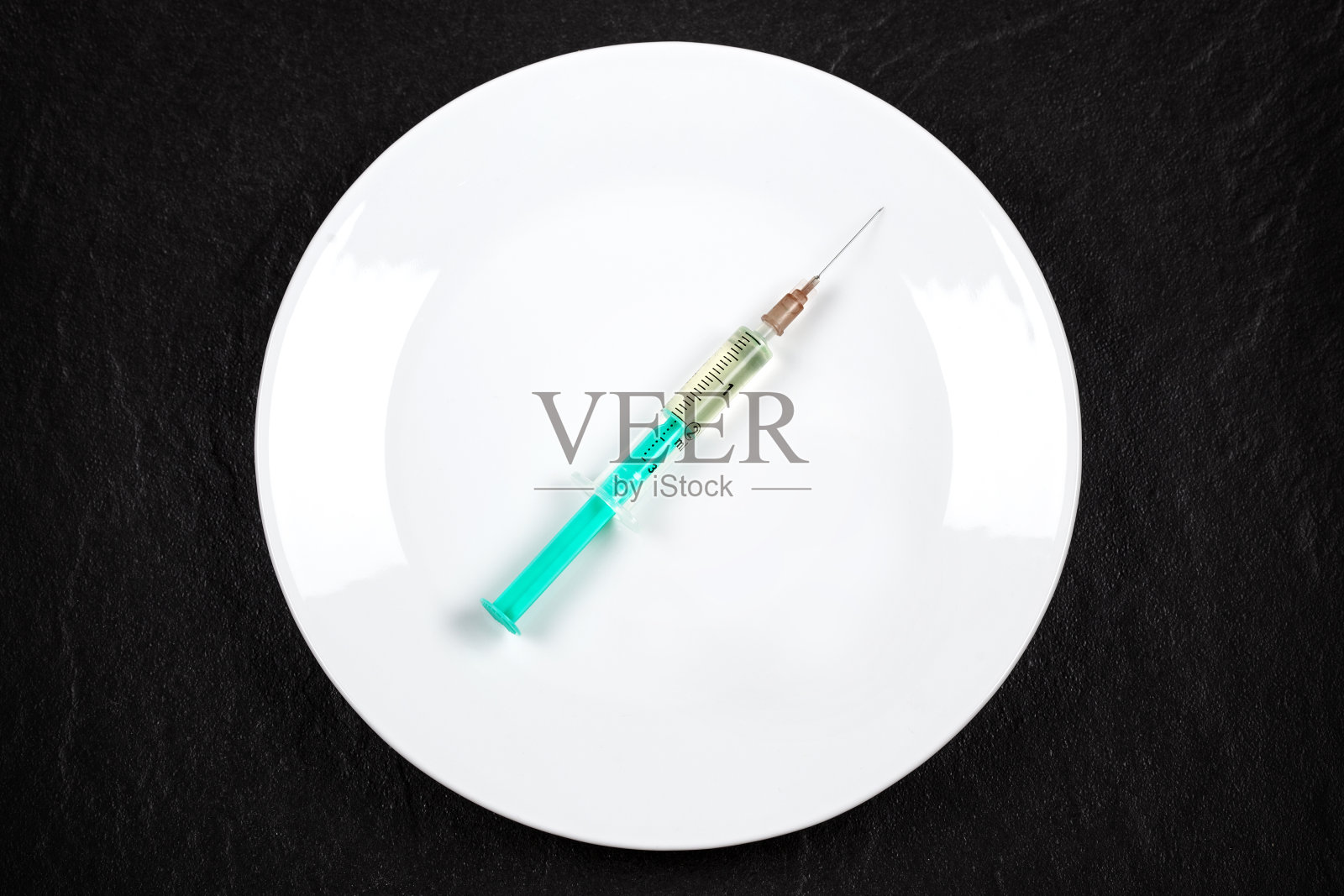 注射器放在白色盘子上照片摄影图片