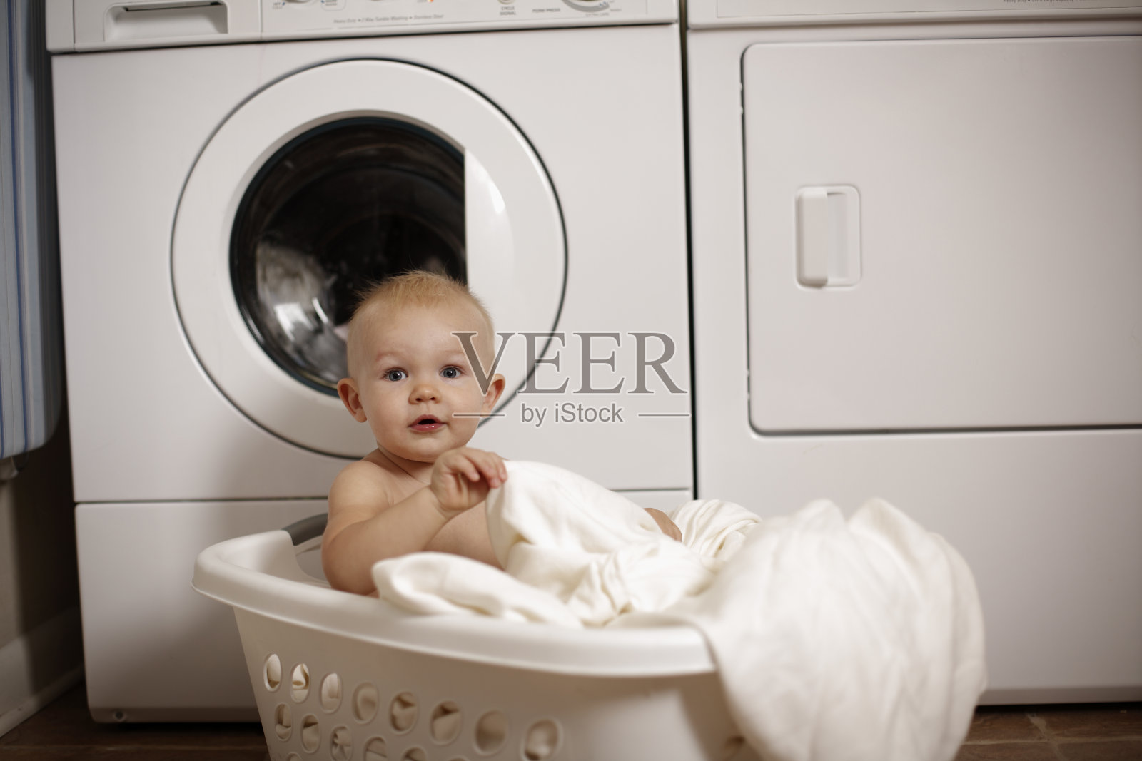 小男孩在洗衣篮里玩照片摄影图片