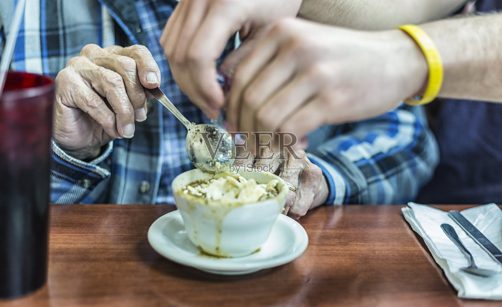 孙子帮爷爷把饼干弄碎放进蔬菜汤里照片摄影图片