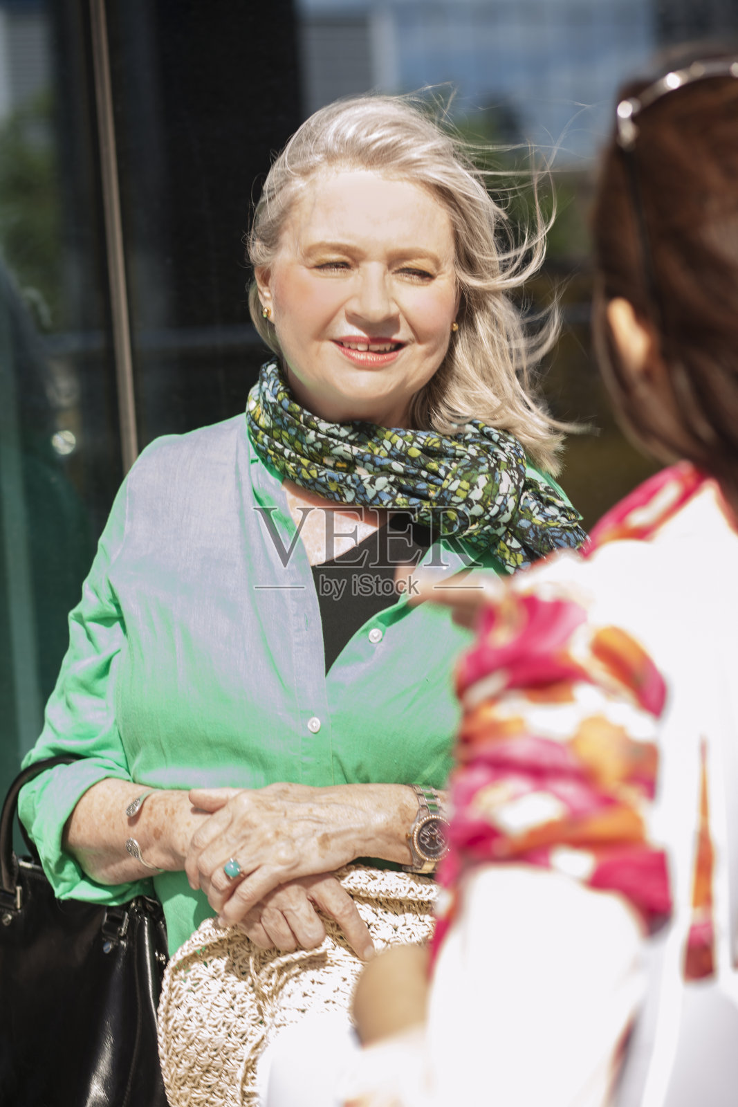 一位年长的成年妇女在市区和朋友聊天。照片摄影图片