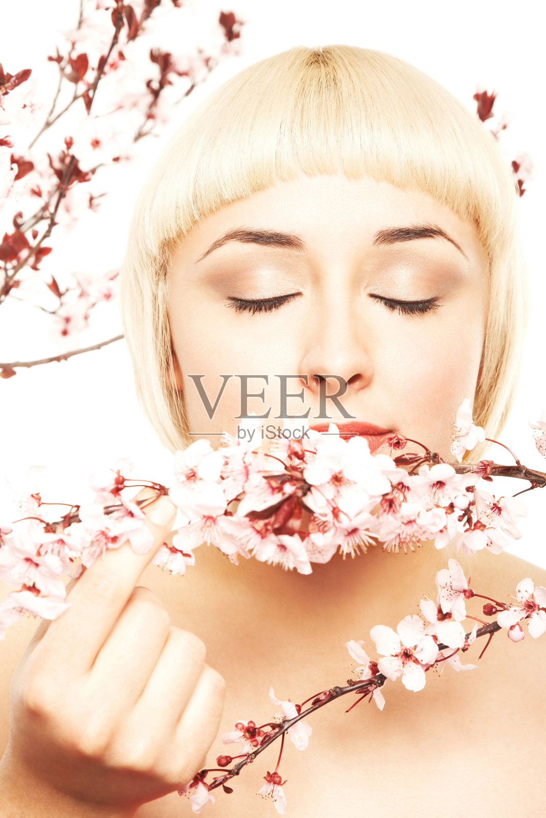 迷人的女人闻着粉红色的樱花照片摄影图片