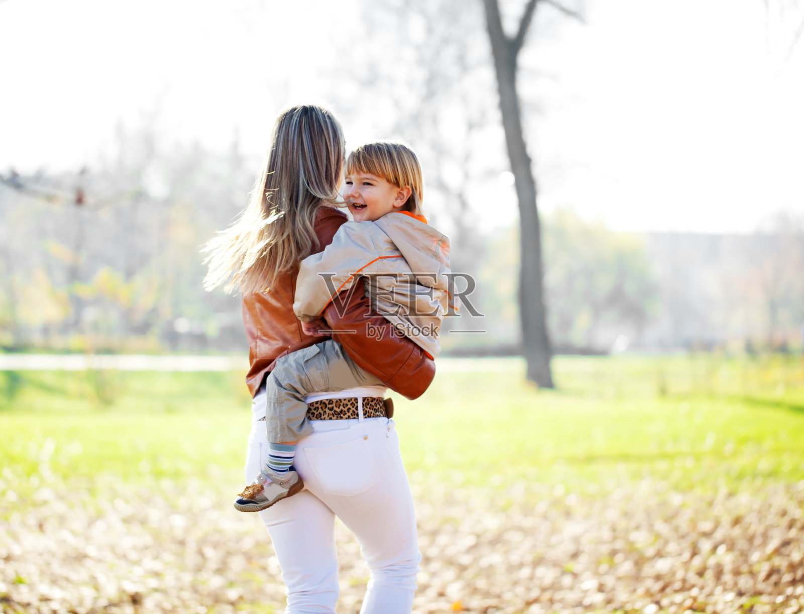 妈妈带着儿子在公园里散步。照片摄影图片