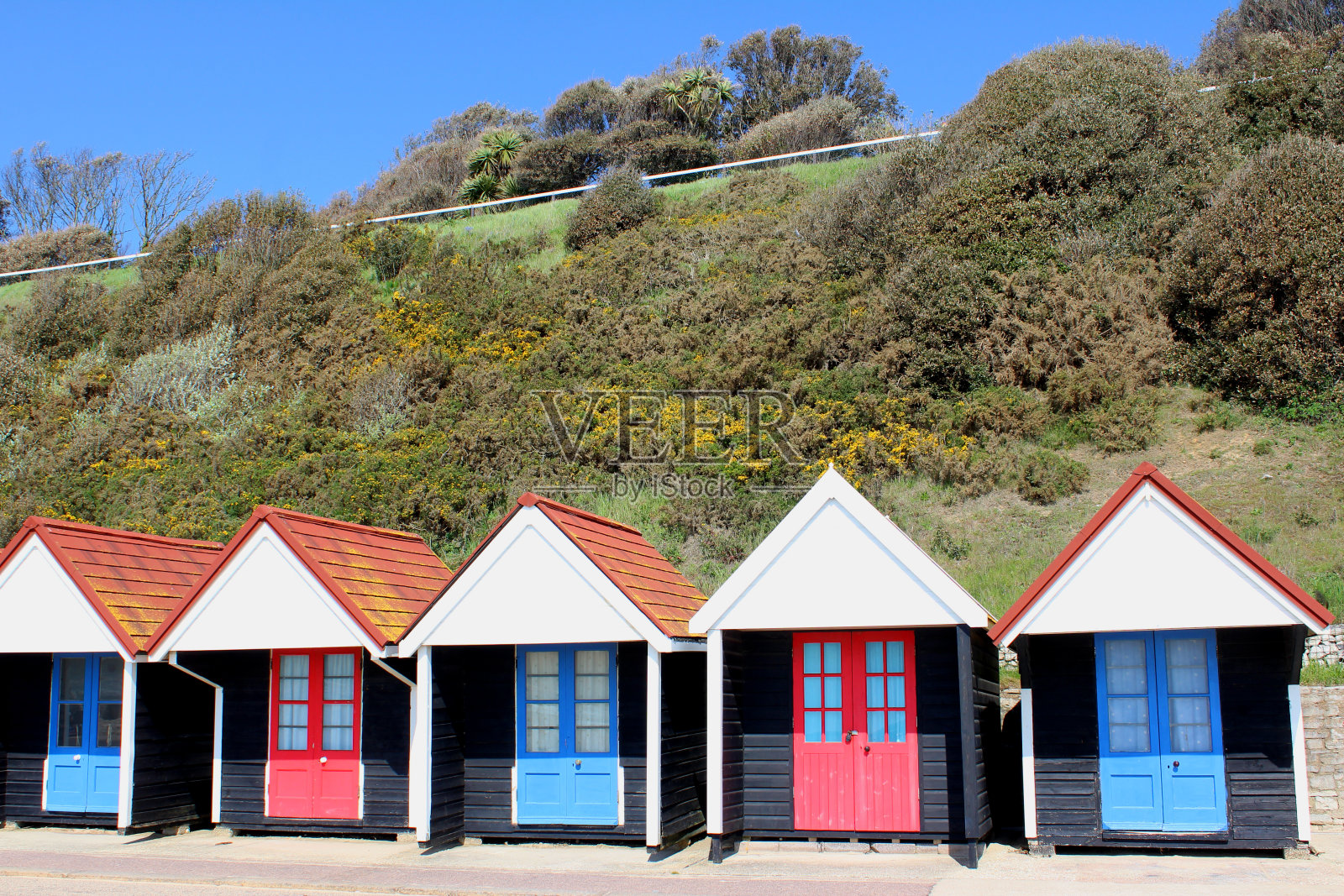 色彩斑斓的英国海滩小屋旁边的悬崖照片摄影图片