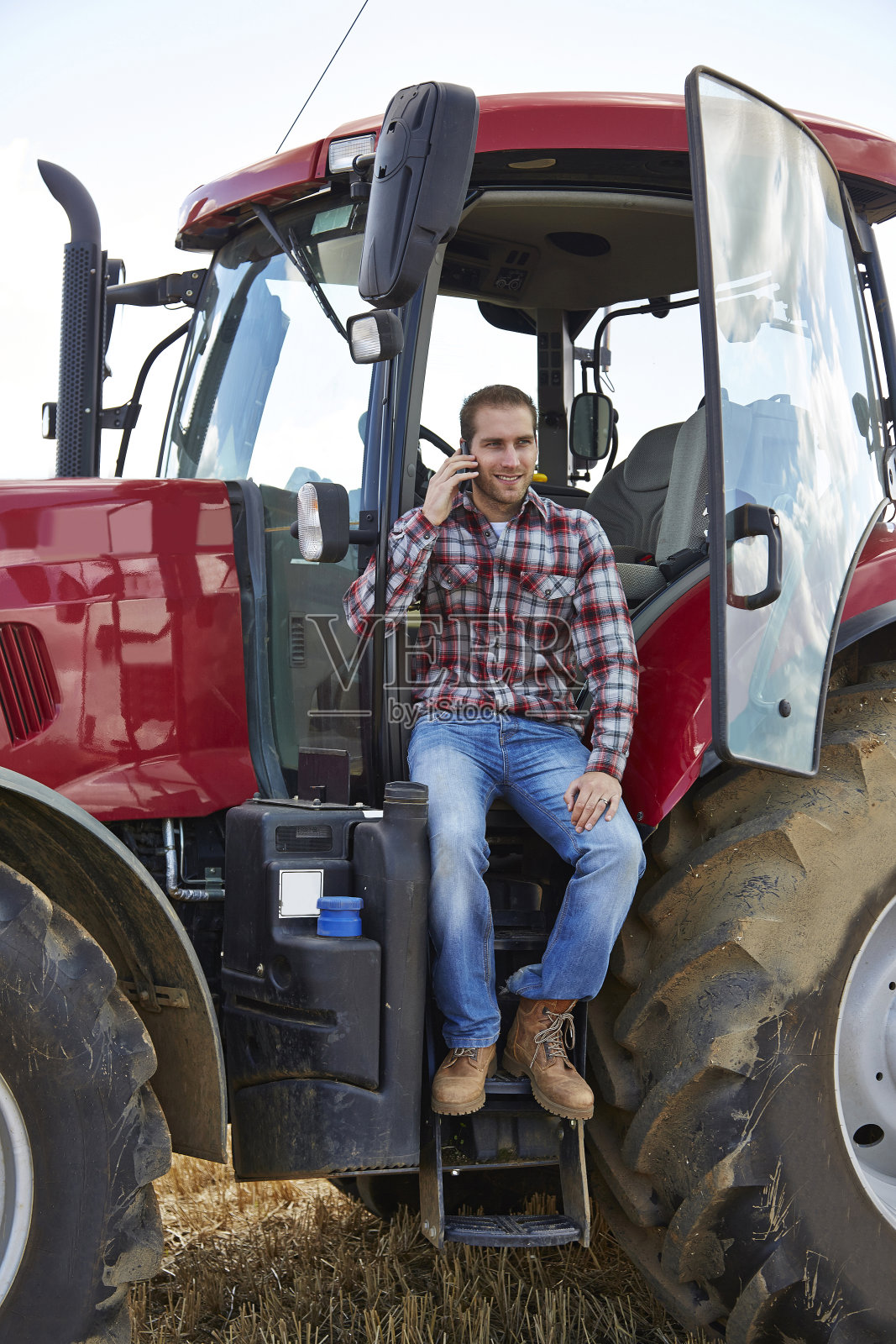 农夫坐在拖拉机驾驶室里打手机照片摄影图片