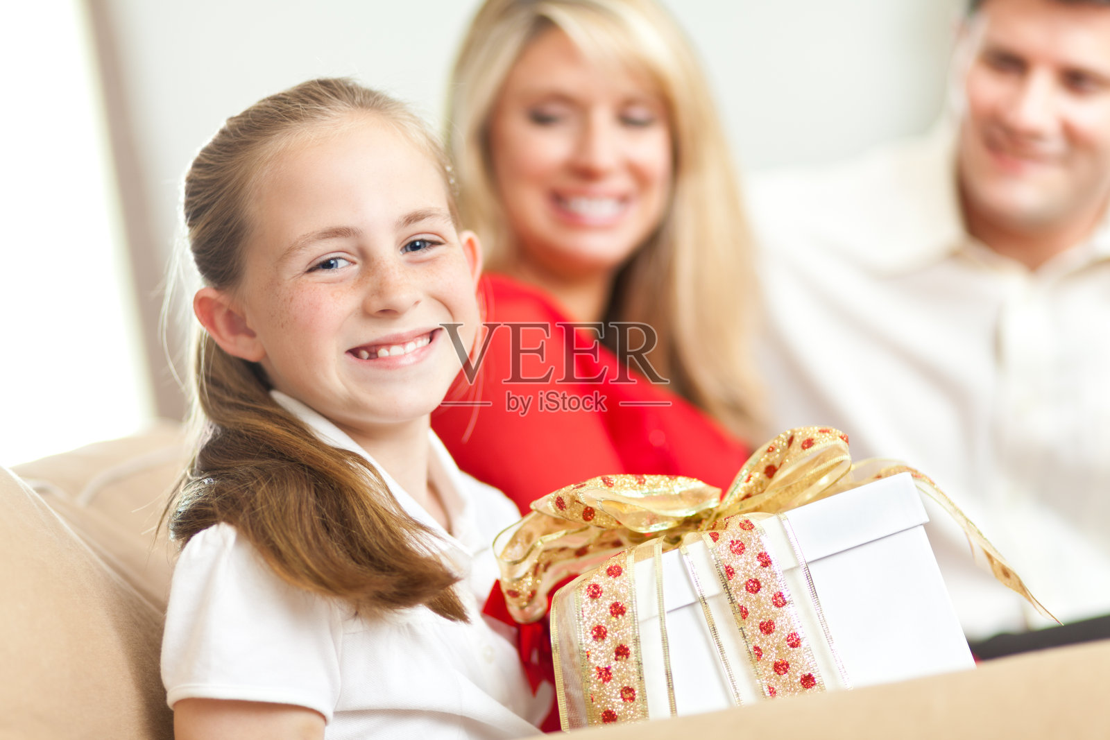 一个微笑着拿着礼物的小女孩在客厅里照片摄影图片