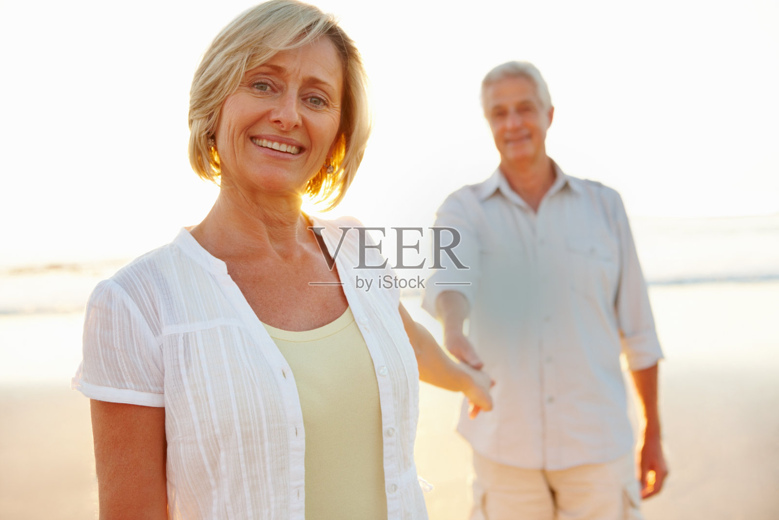 一对快乐的老夫妇在海滩上漫步照片摄影图片