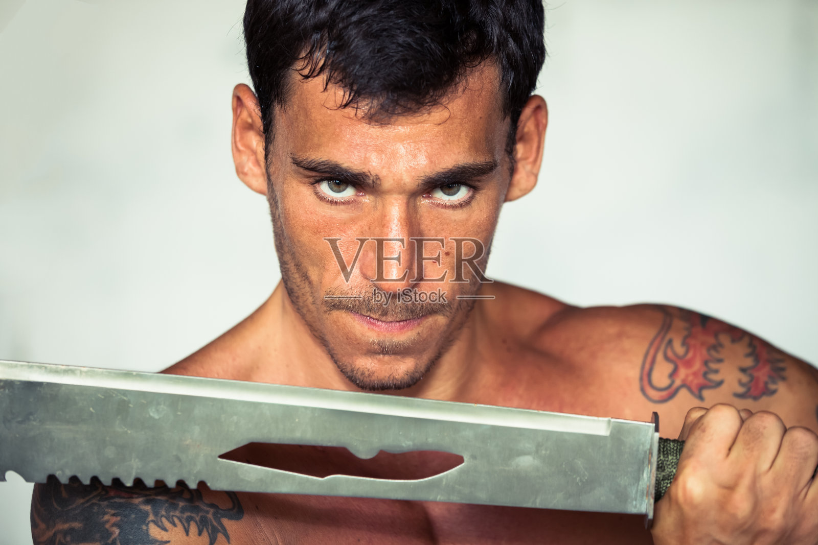 剑刃后面有纹身的肌肉战士照片摄影图片