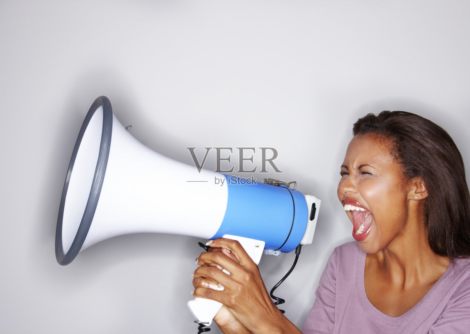 年轻女人对着扩音器大喊大叫照片摄影图片