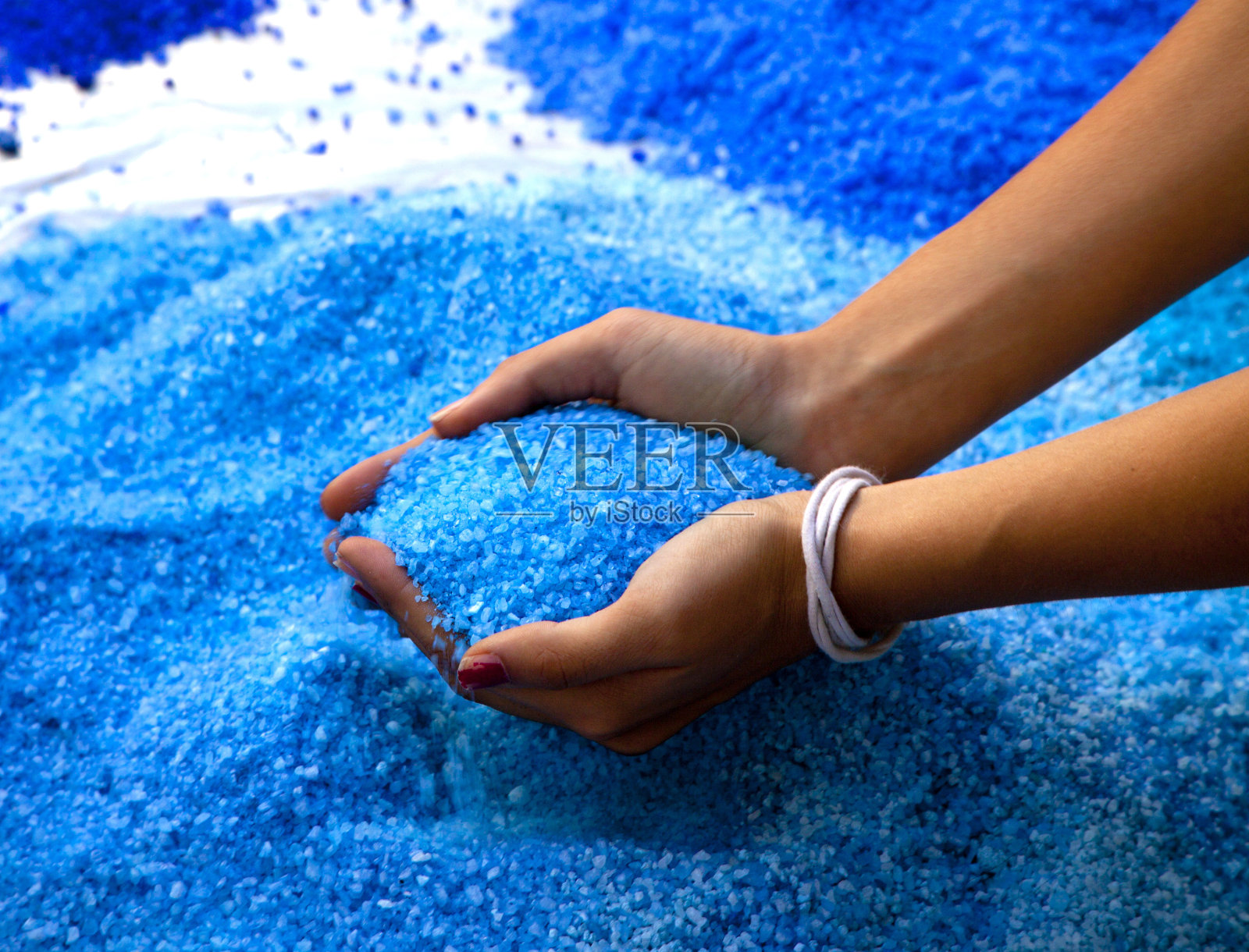 手里拿着蓝色的盐。照片摄影图片