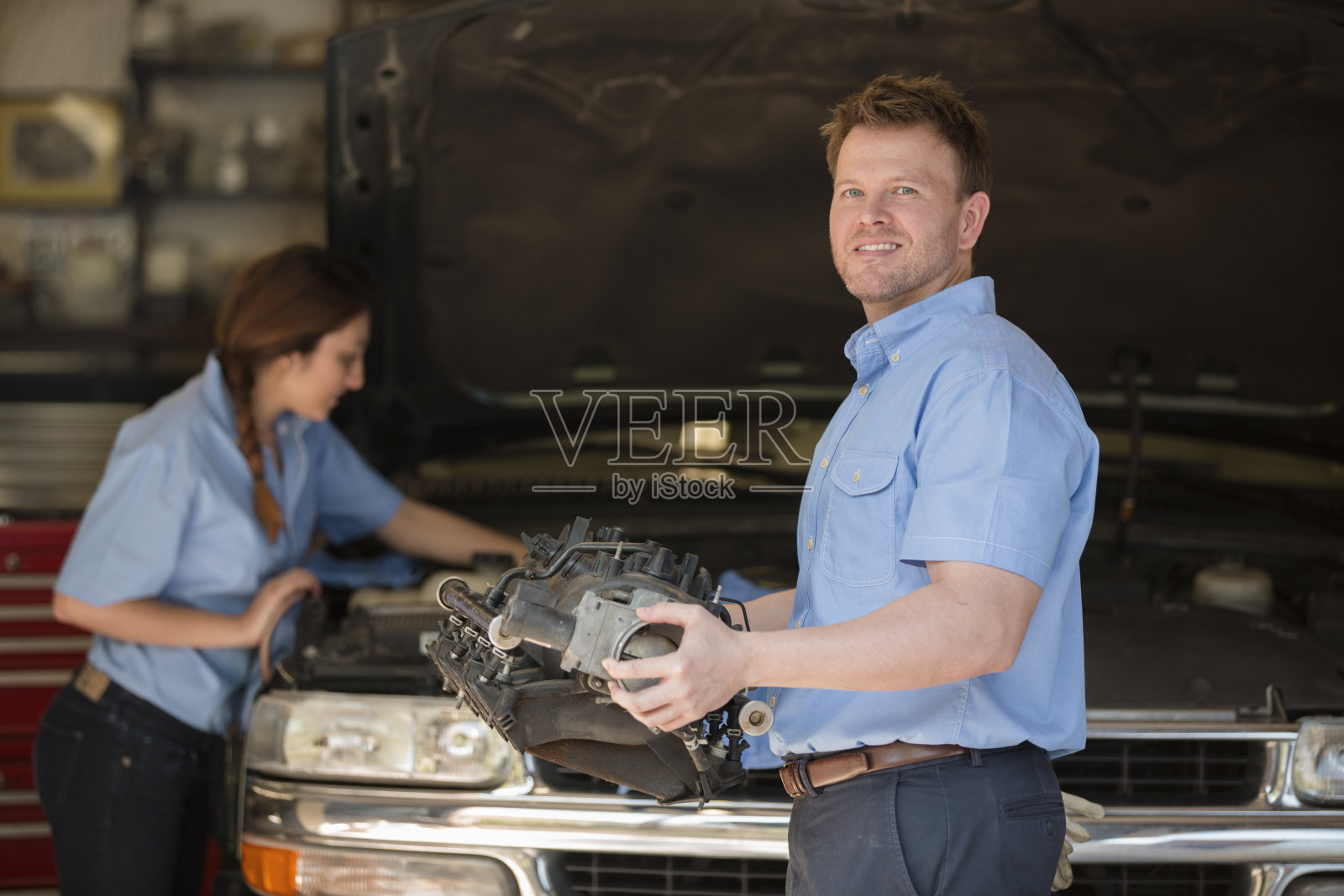 机械师在一家汽车修理厂工作。男人、女人工作。照片摄影图片